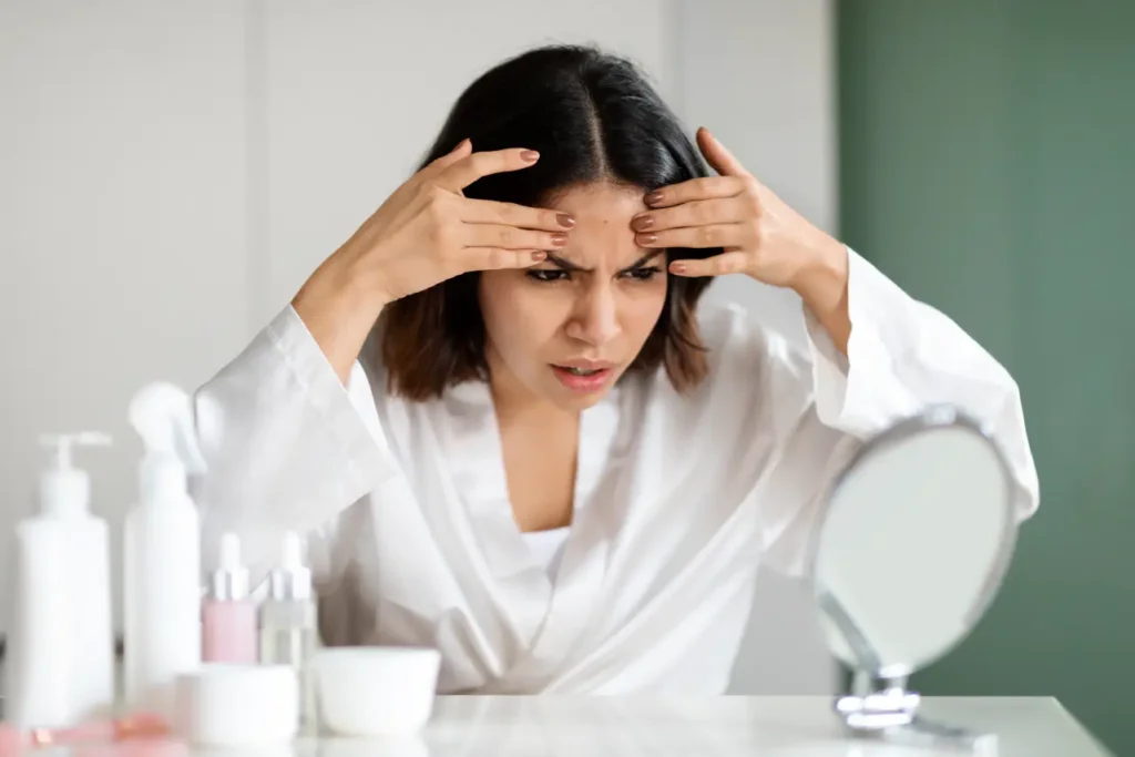 Woman examining forehead lines while considering anti ageing facials