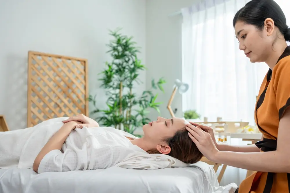  Therapist giving a relaxing Bojin treatment to a client on a spa bed in a bright wellness treatment room