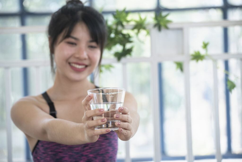 Woman holding a glass of water to promote healthy hydration and support the body's natural detoxification processes
